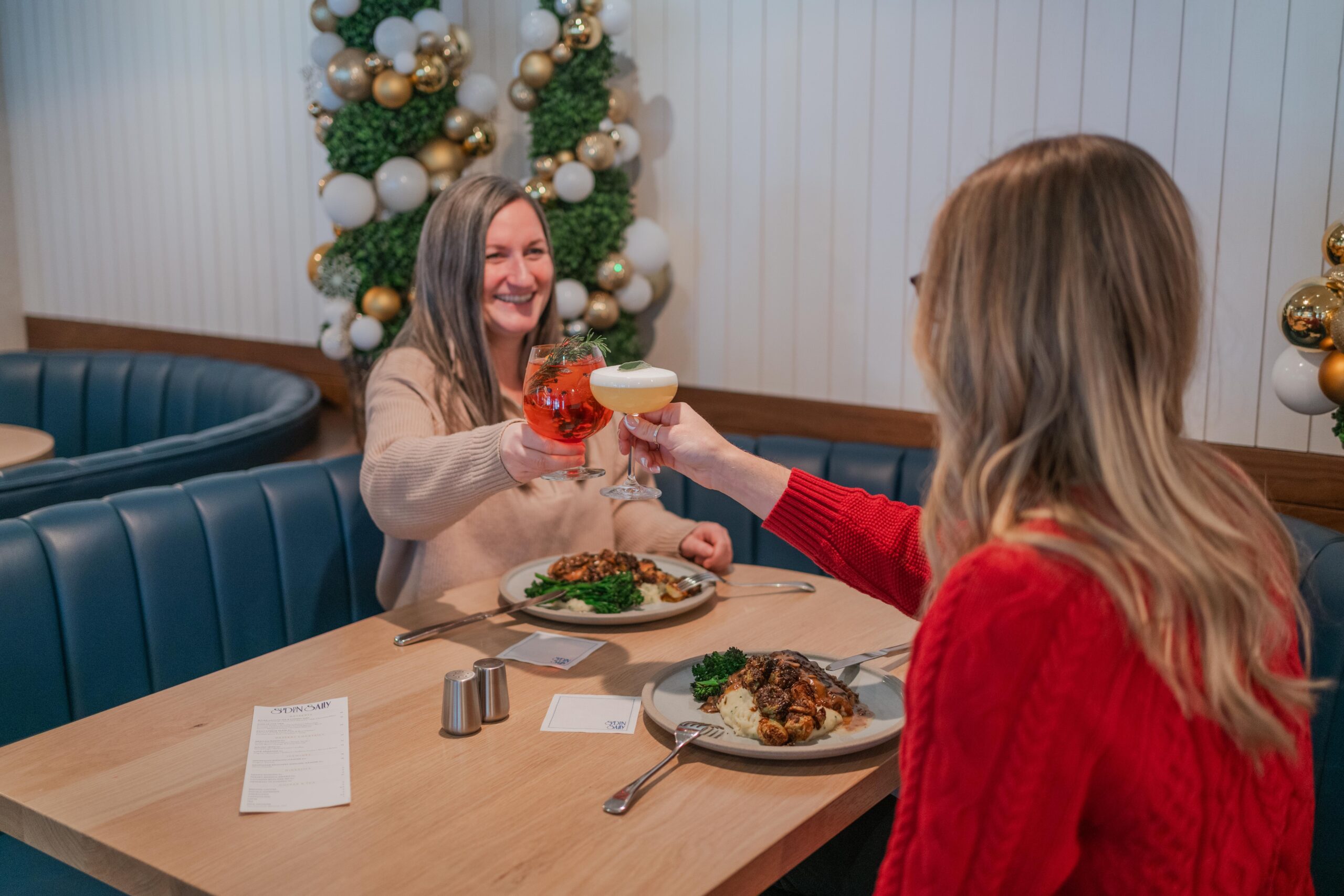 two women dining at sudden sally restaurant clinking beverages over turkey dinner